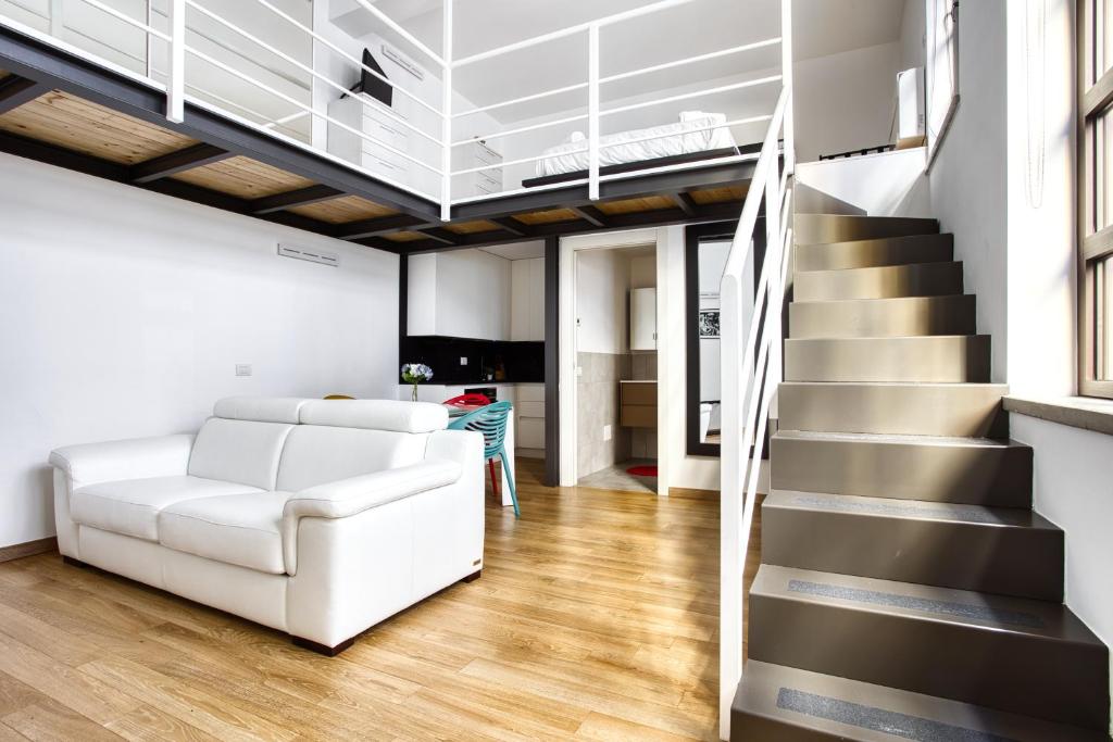 ein Wohnzimmer mit einer weißen Couch und einer Treppe in der Unterkunft JOIVY Charismatic 1-bed flat with parking in Mailand