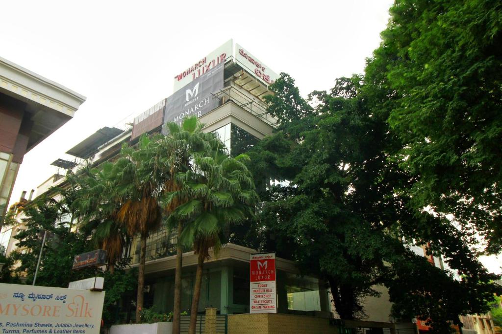 a building with a palm tree in front of it at Monarch Luxur - Infantry Road in Bangalore