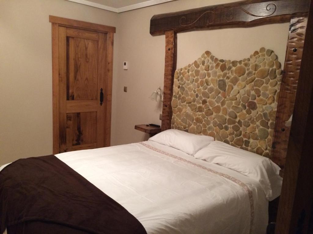 a bedroom with a large bed with a wooden headboard at Posada el Molino de Cadalso in Cereceda