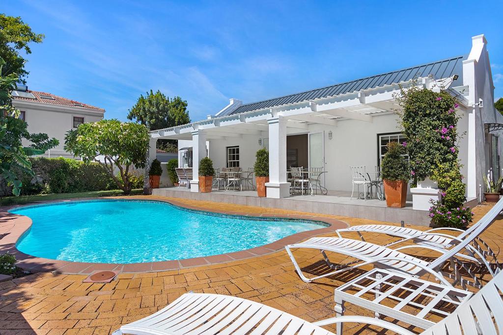 einen Pool mit Stühlen und ein Haus in der Unterkunft Morningside Cottage in Tokai