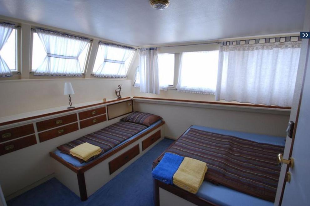 a small bedroom with two beds and windows at Motor Yacht Cadabra in Rab