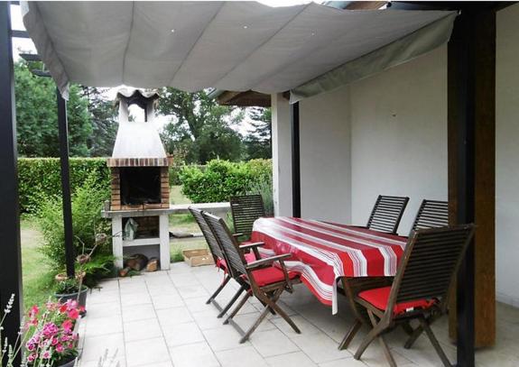 eine Terrasse mit einem Tisch, Stühlen und einem Kamin in der Unterkunft Belle de jour in Mézos