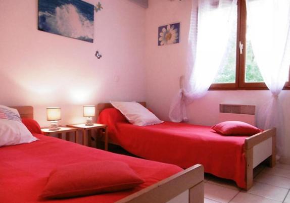 1 Schlafzimmer mit 2 roten Betten und einem Fenster in der Unterkunft Belle de jour in Mézos