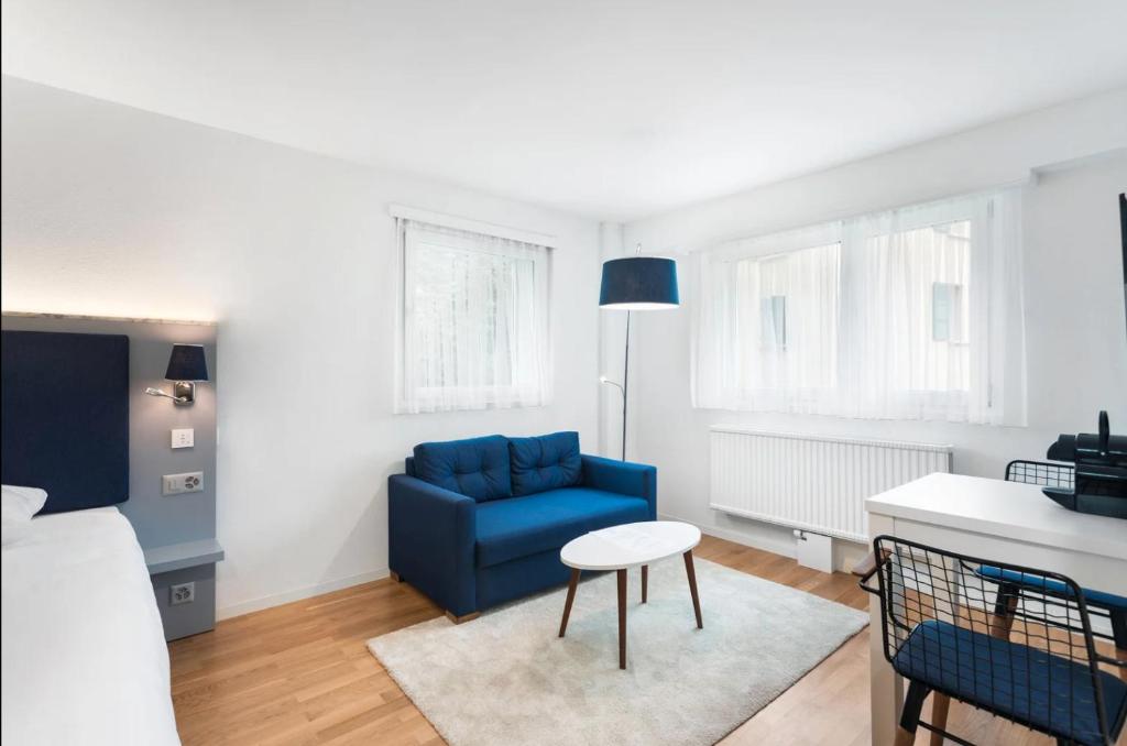 sala de estar con sofá azul y mesa en Sallaz Residence by Homenhancement, en Lausana
