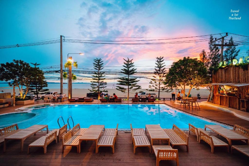 uma piscina com mesas e cadeiras em frente a um pôr-do-sol em Zand Morada Pattaya em Praia de Jomtien