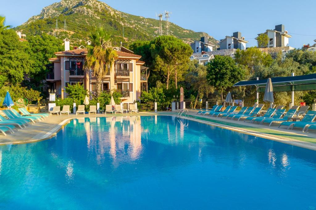 una piscina con sillas azules y una montaña en Club Pink Palace Hotel, en Ölüdeniz