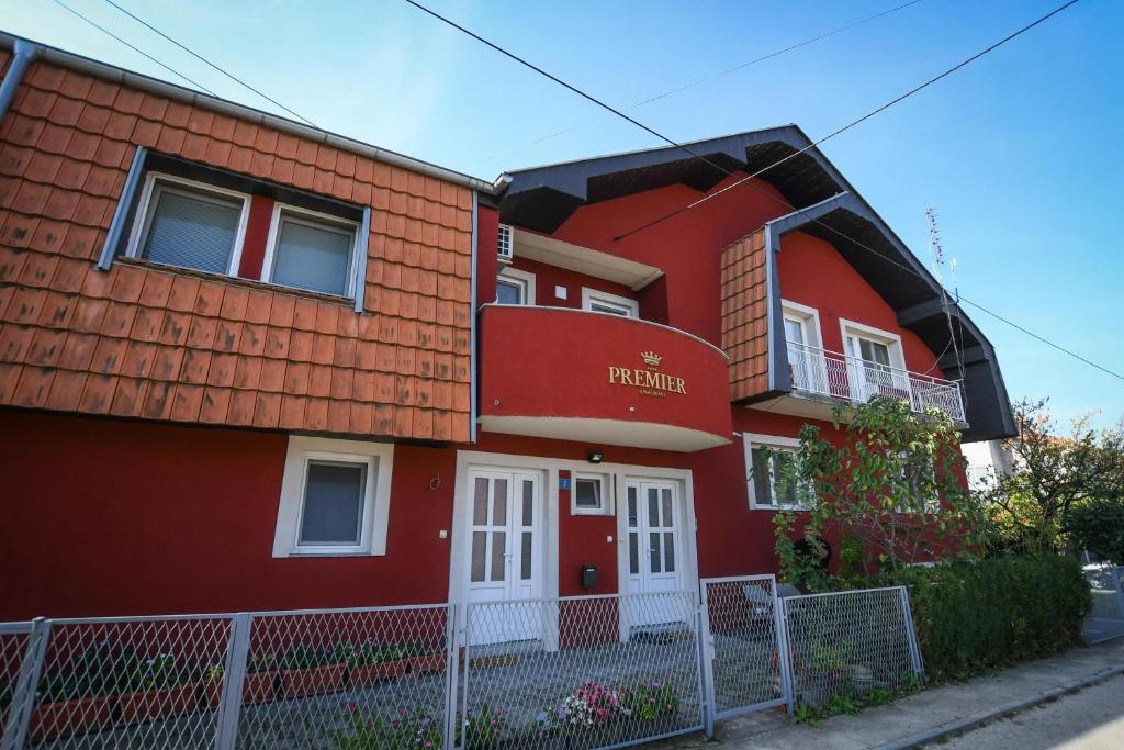 ein rotes Haus mit einem Zaun davor in der Unterkunft Premier apartments in Kladovo