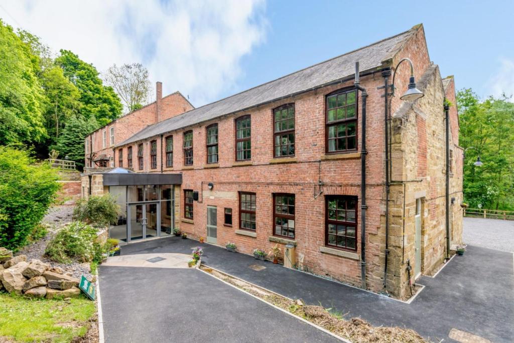 an old red brick building with a driveway at Cote Ghyll Mill at Osmotherley in Ingleby Arncliffe