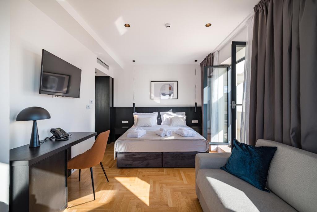 a bedroom with a bed and a desk and a couch at Miramare Hotel in Zadar