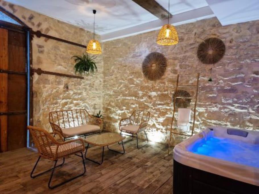 Habitación con bañera de hidromasaje, sillas y mesa. en Gîte « domaine de l’oustal nau », en Peyriac-de-Mer