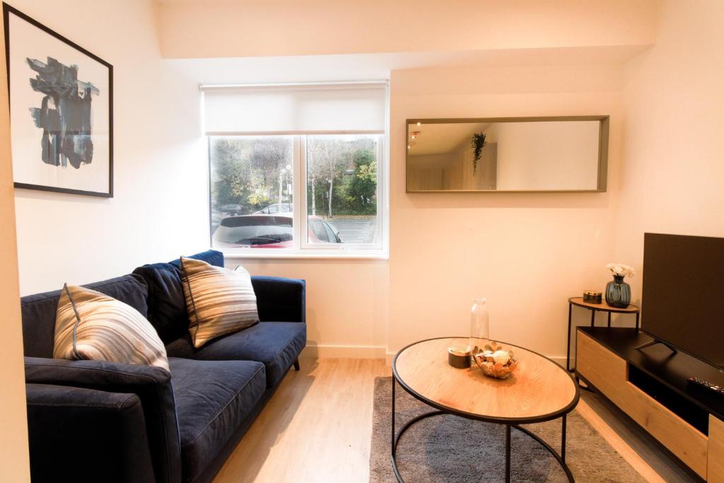 a living room with a blue couch and a table at Redhill Apartments by Pay As U Stay in Redhill