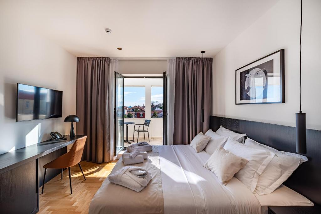 a bedroom with a large bed with a desk and a desk at Miramare Hotel in Zadar