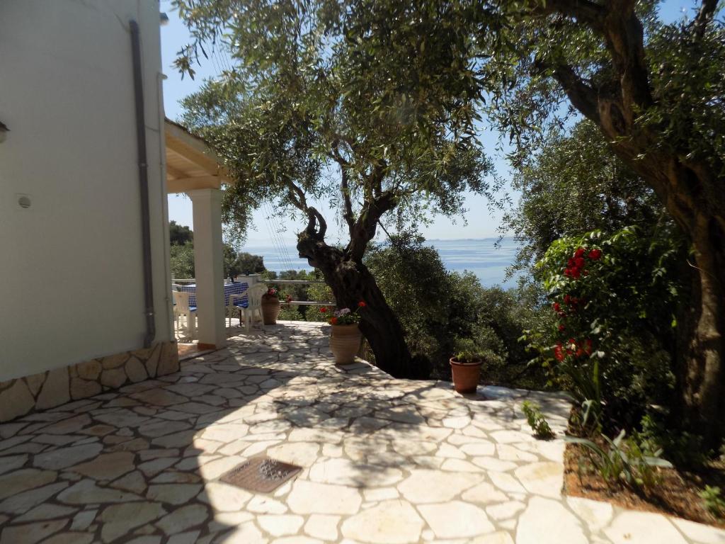 una pasarela de piedra con un gran árbol frente a una casa en villa elli panoramic view 2, en Ýpsos