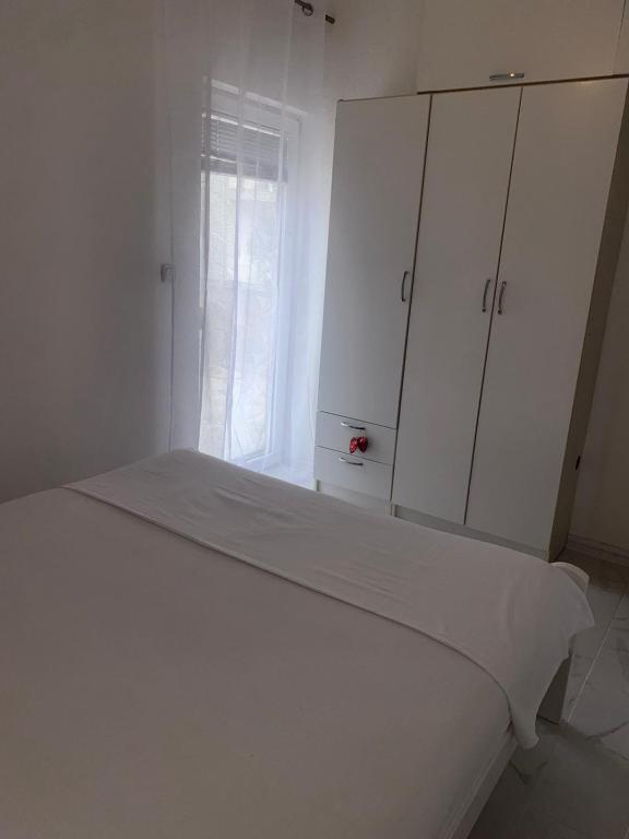 a white bedroom with a bed and a window at Apartman Jaca in Mrčevac