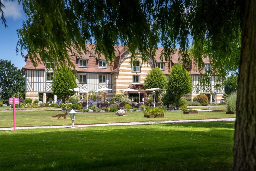 a large pink building with a dog in a park at Le Manoir De La Poterie & Spa in Cricquebœuf
