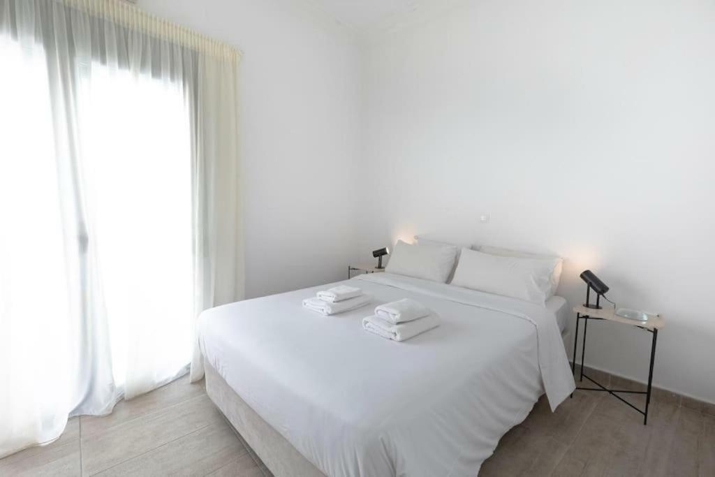 a white bedroom with a large white bed and a window at Athens Tower 2 Bedroom Apartment by SuperHost Hub in Athens