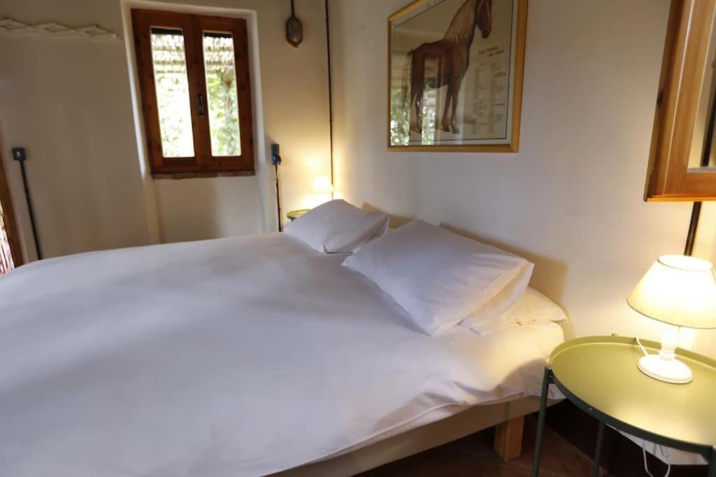 1 cama blanca en un dormitorio con 2 lámparas en Campigallino, casa immersa nella natura., en Casale Marittimo