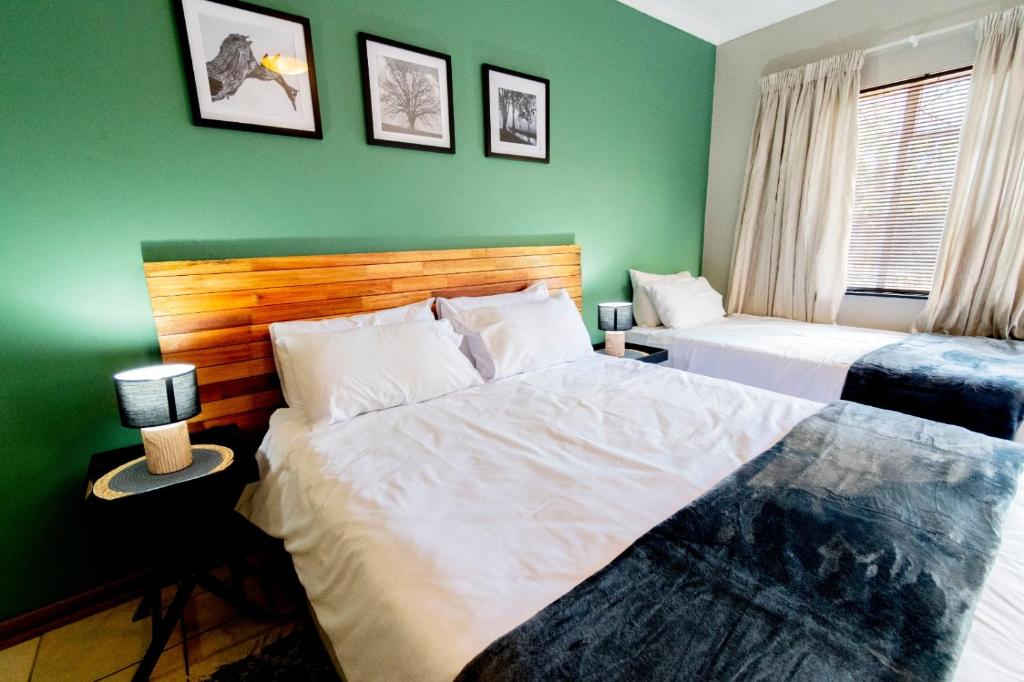 a bedroom with two beds and a green wall at Mulkana in Bloemfontein