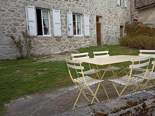 einen Tisch und Stühle vor einem Gebäude in der Unterkunft Chambre indépendante - style studio - avec jardin à la campagne in Junhac