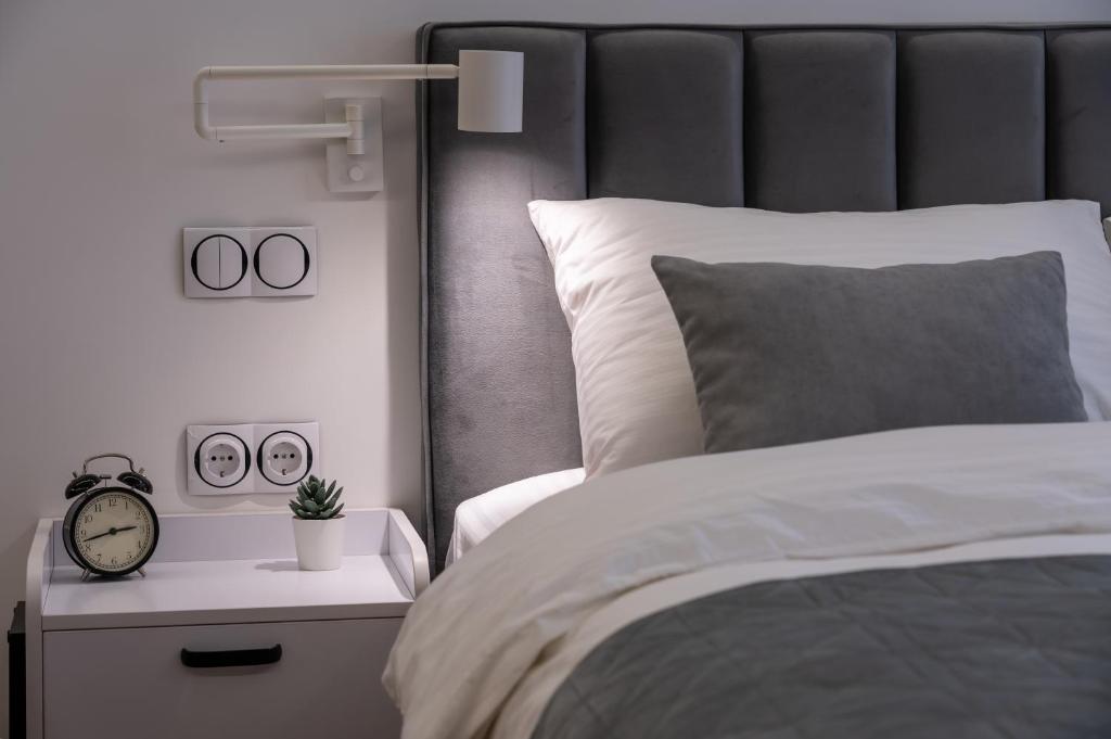 a bedroom with a bed and a clock on a night stand at Shades of gray - NEW DELUX Apartments in Kyiv