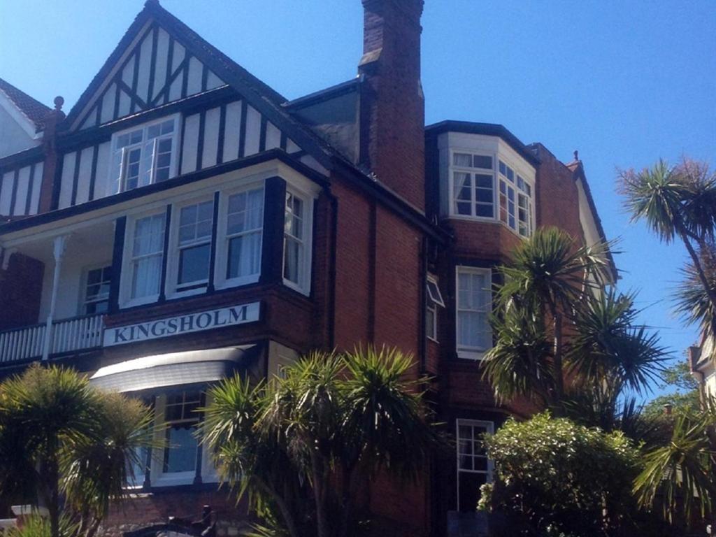 a large brick building with palm trees in front of it at Kingsholm Guest House in Torquay