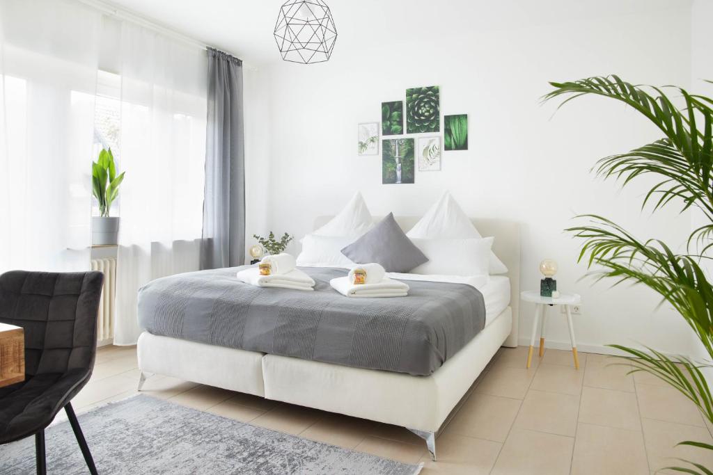 - une chambre blanche avec un lit et une chaise dans l'établissement IDEE Living Design Apartment Balkon - Netflix - 6 Pers, à Walldorf