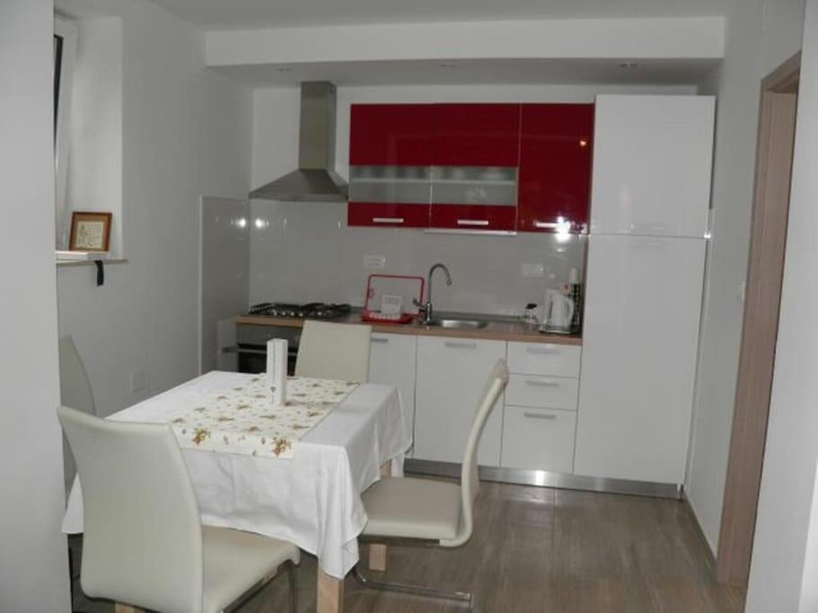 a kitchen with a table and chairs and a kitchen with red cabinets at Apartman Modric Draga in Mošćenička Draga