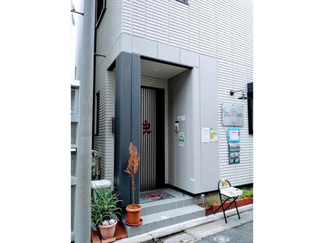 Tokyo stay Hut SARI - Vacation STAY 27260v في طوكيو: باب مبنى فيه نباتات وكرسي