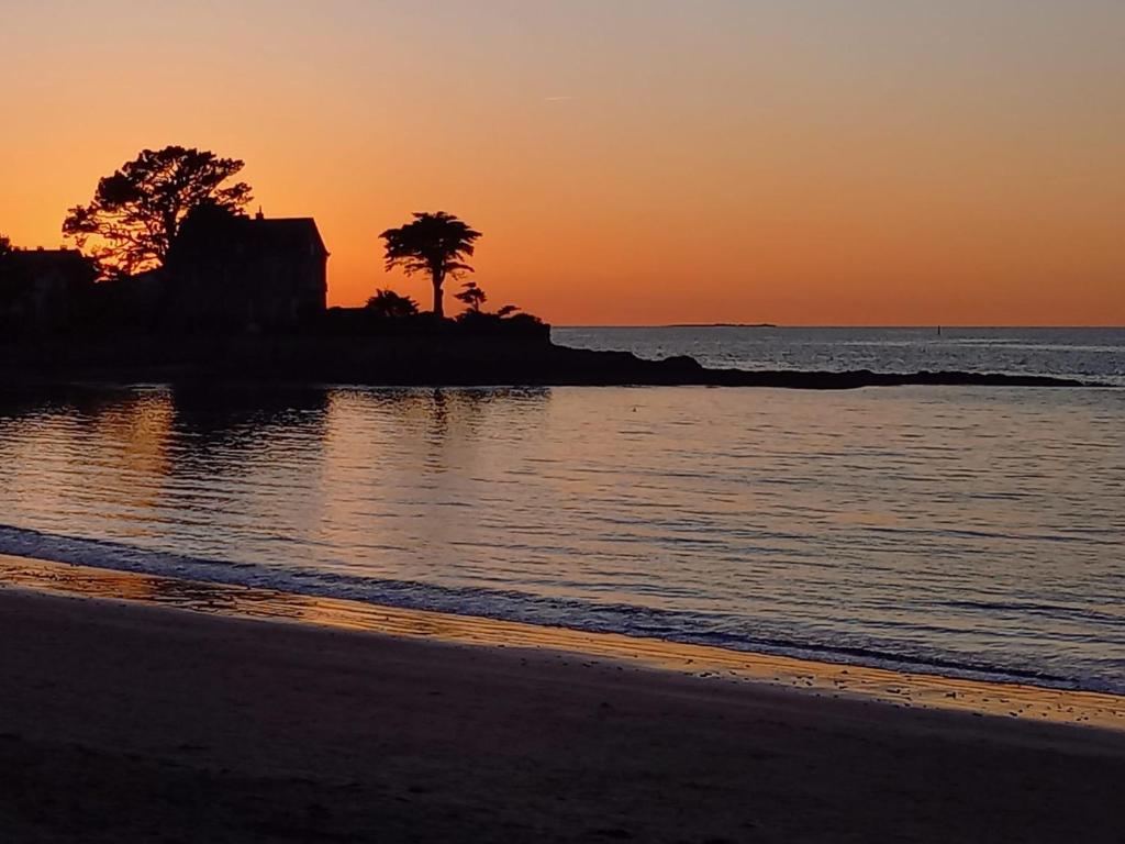 una spiaggia con alberi e l'oceano al tramonto di Maison neuve - Mesquer - Plage, Rando, Vélo a Mesquer