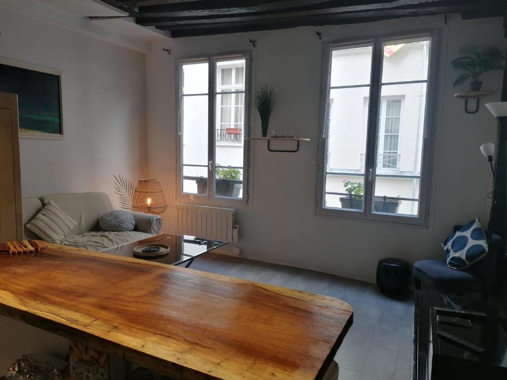 ein Wohnzimmer mit einem Holztisch und 2 Fenstern in der Unterkunft Appartement St Martin in Paris