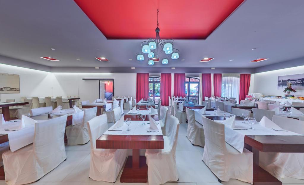 restauracja z białymi stołami i krzesłami oraz żyrandolem w obiekcie Hotel Villa Donat w mieście Sveti Filip i Jakov