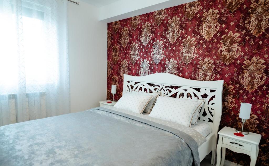a bedroom with a bed and a red wall at Carla's Apart Palas-Hala Centrala 1 Bedroom, airport shuttle in Iaşi