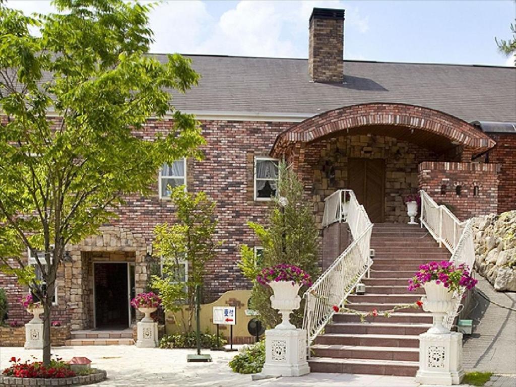 a brick building with stairs and flowers in front of it at Rokugatsu-no-Mori Auberge in Sano