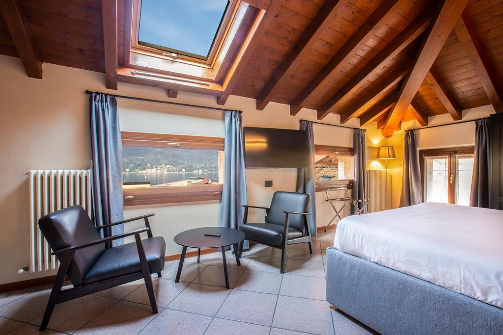 a bedroom with a bed and two chairs and a window at Antico Pozzo Apartment in Bellagio