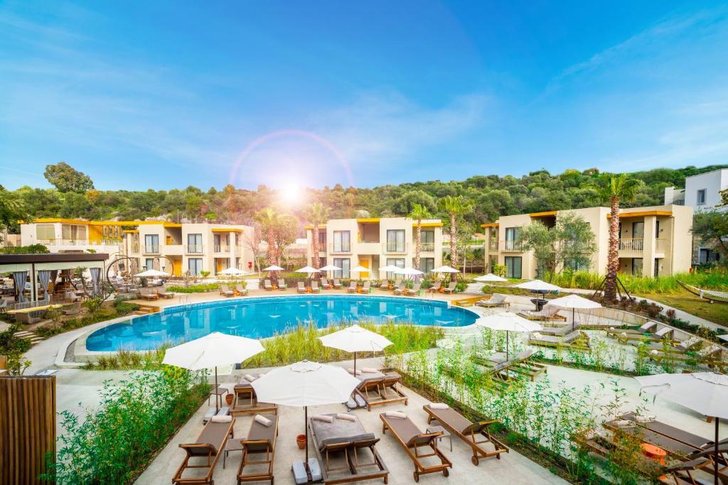 uma imagem de uma piscina num resort com mesas e guarda-sóis em Helis Suites Bitez em Bodrum City