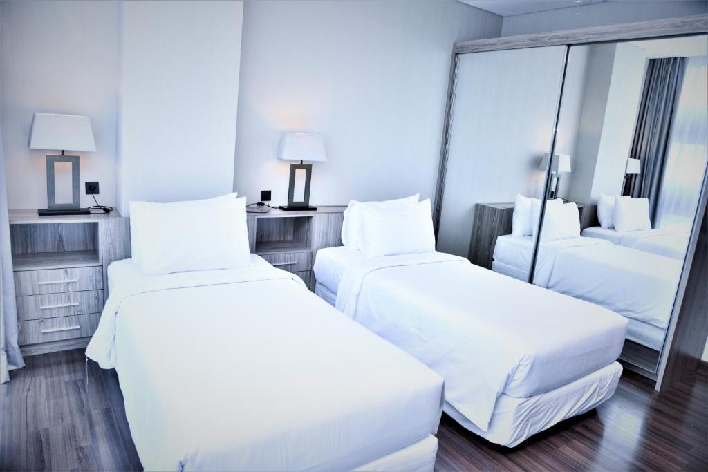 a hotel room with two beds and a mirror at Azana Suites Hotel Antasari in Jakarta
