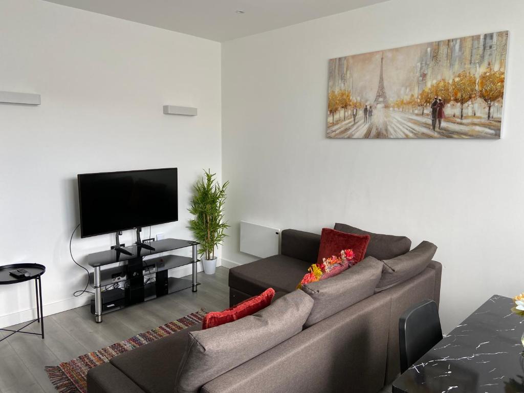 a living room with a couch and a flat screen tv at Lovely 2 Double Bedroom Flat with free parking - At the Atrium MK in Milton Keynes