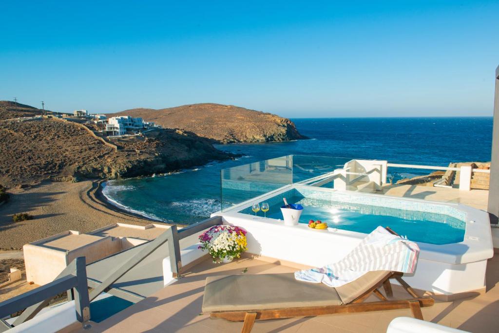 a balcony with a pool and chairs and the ocean at Myrsini's Luxury Suites Merchia in Mýkonos City