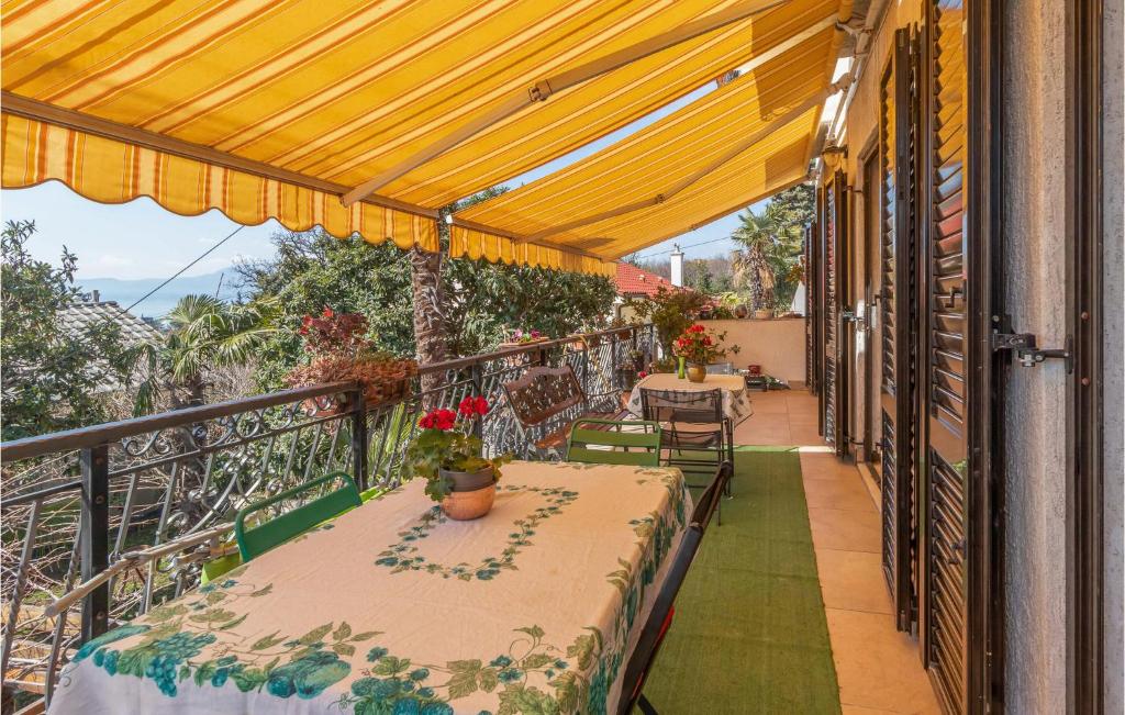 un balcone con tavoli, sedie e baldacchino giallo di Pet Friendly Apartment In Kostrena With Kitchen a Kostrena (Costrena)