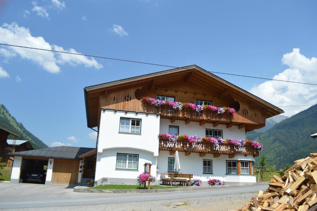 une maison blanche avec des fleurs sur le balcon dans l'établissement Apart Lorenz, à Häselgehr