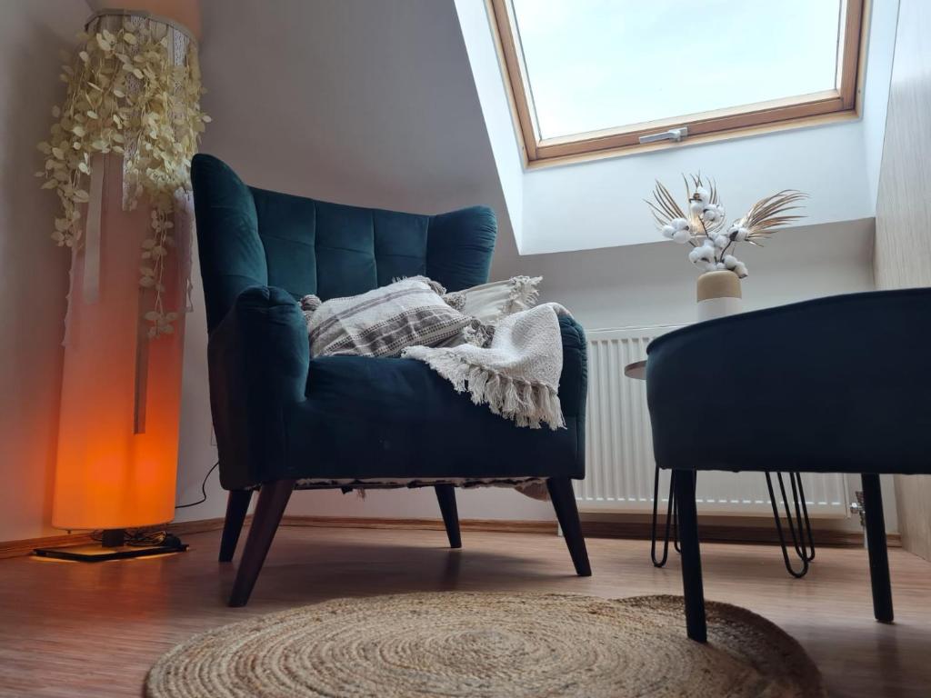 uma cadeira azul com um cobertor numa sala em Apartamenty "Hubertówka" 