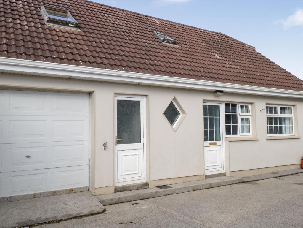 un garaje con puertas blancas y techo marrón en Ring Fort Cottage, en Longford