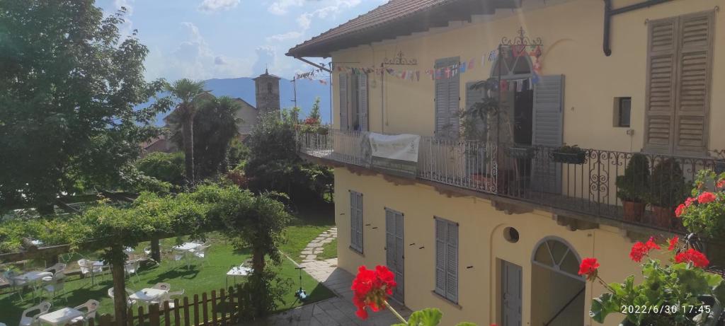 a building with a balcony and a yard at Ostello del Quadrifoglio in Ameno