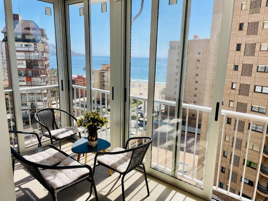 uma varanda com cadeiras e uma mesa em frente às janelas em Martina Maria Beach em Benidorm