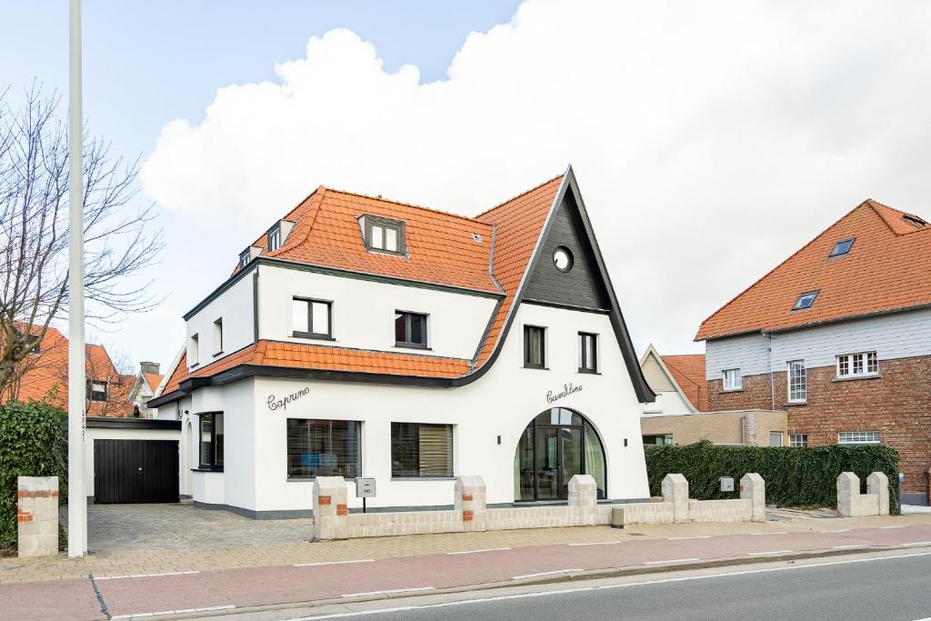 ein großes weißes Haus mit orangefarbenem Dach in der Unterkunft CAPRINO Guesthouse in Knokke-Heist