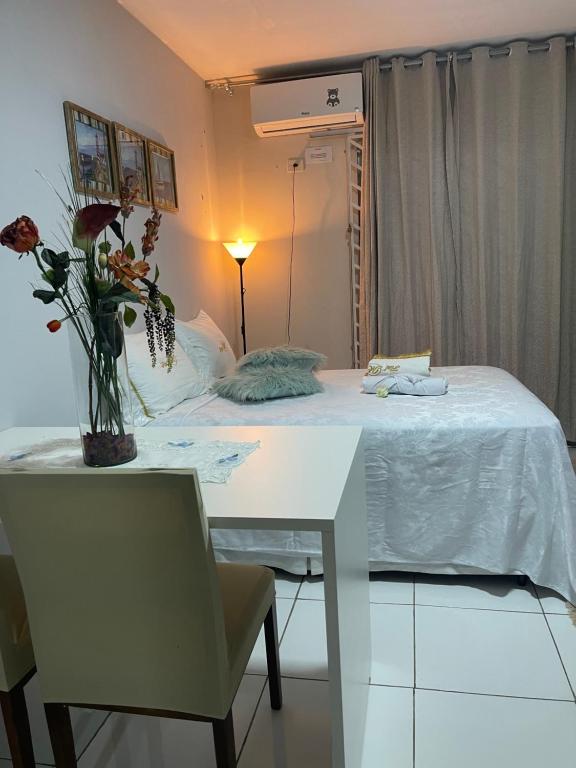 a bedroom with a table and a bed with a vase of flowers at Flat JK 203 in Juazeiro do Norte