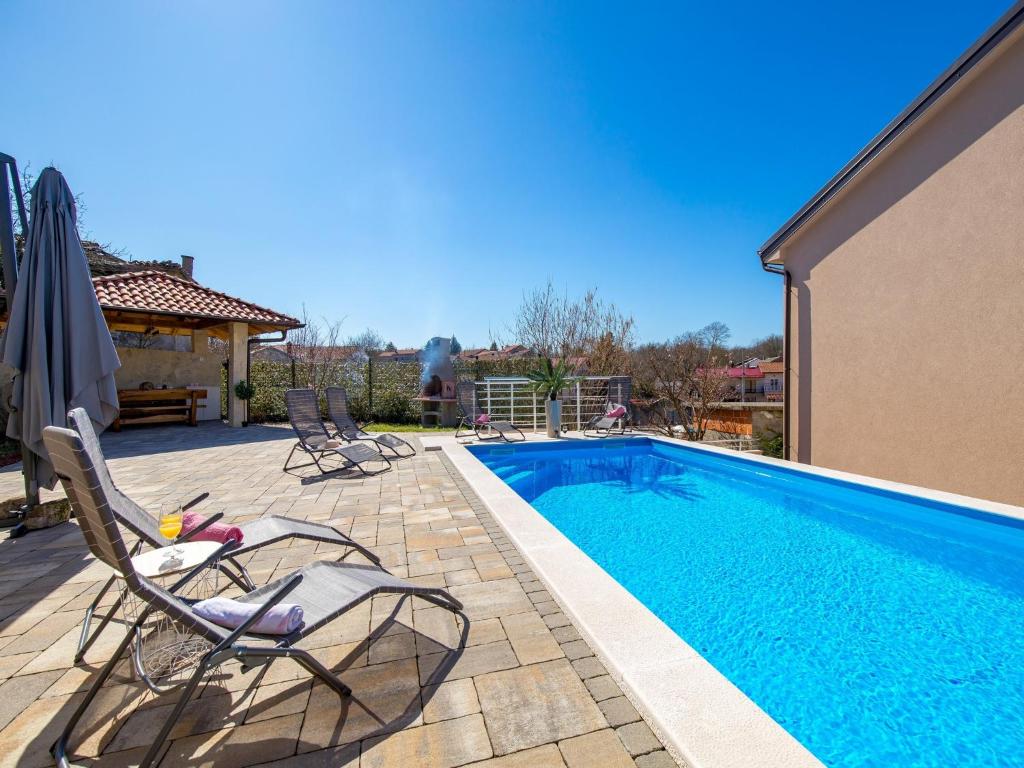 a swimming pool with two chairs next to a house at Villa Lemily in Matulji