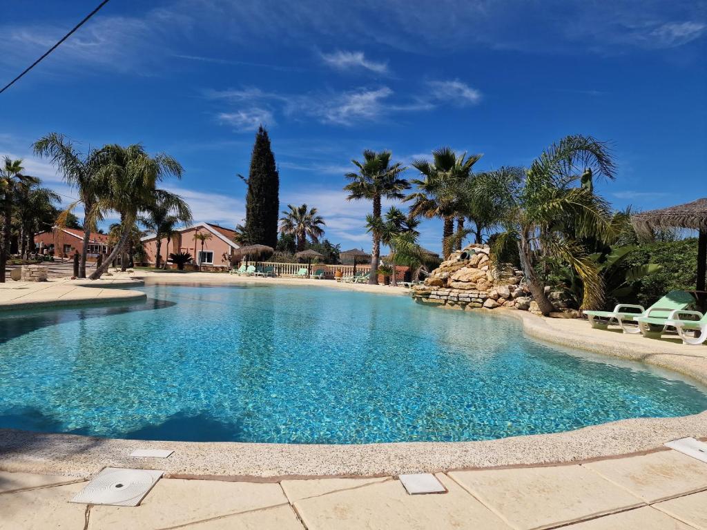 une grande piscine avec de l'eau bleue et des palmiers dans l'établissement Quinta do Baía, à Lagos