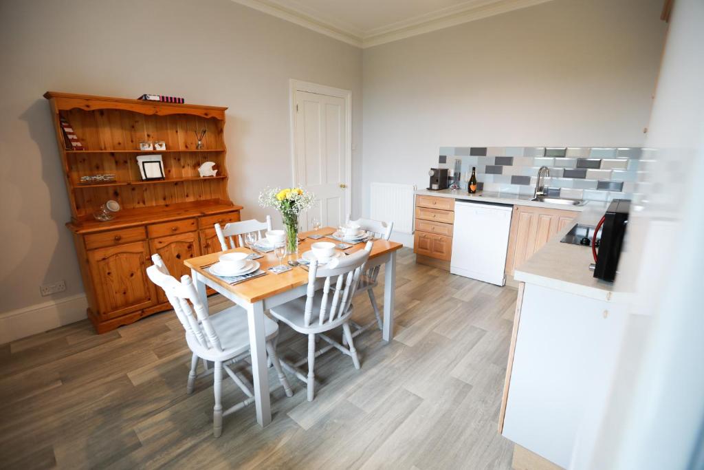 a kitchen with a wooden table and white chairs at Woodside Oak hot tub & pool sleeps 4-6 in Bideford