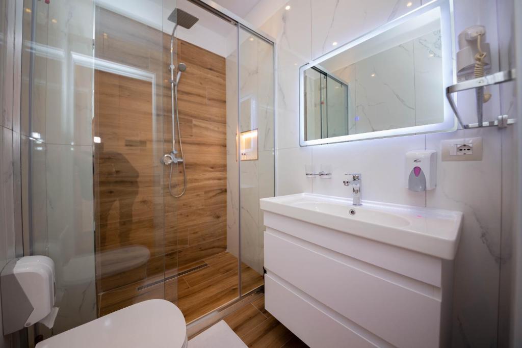 a white bathroom with a sink and a shower at Hotel Vila Misiri in Durrës